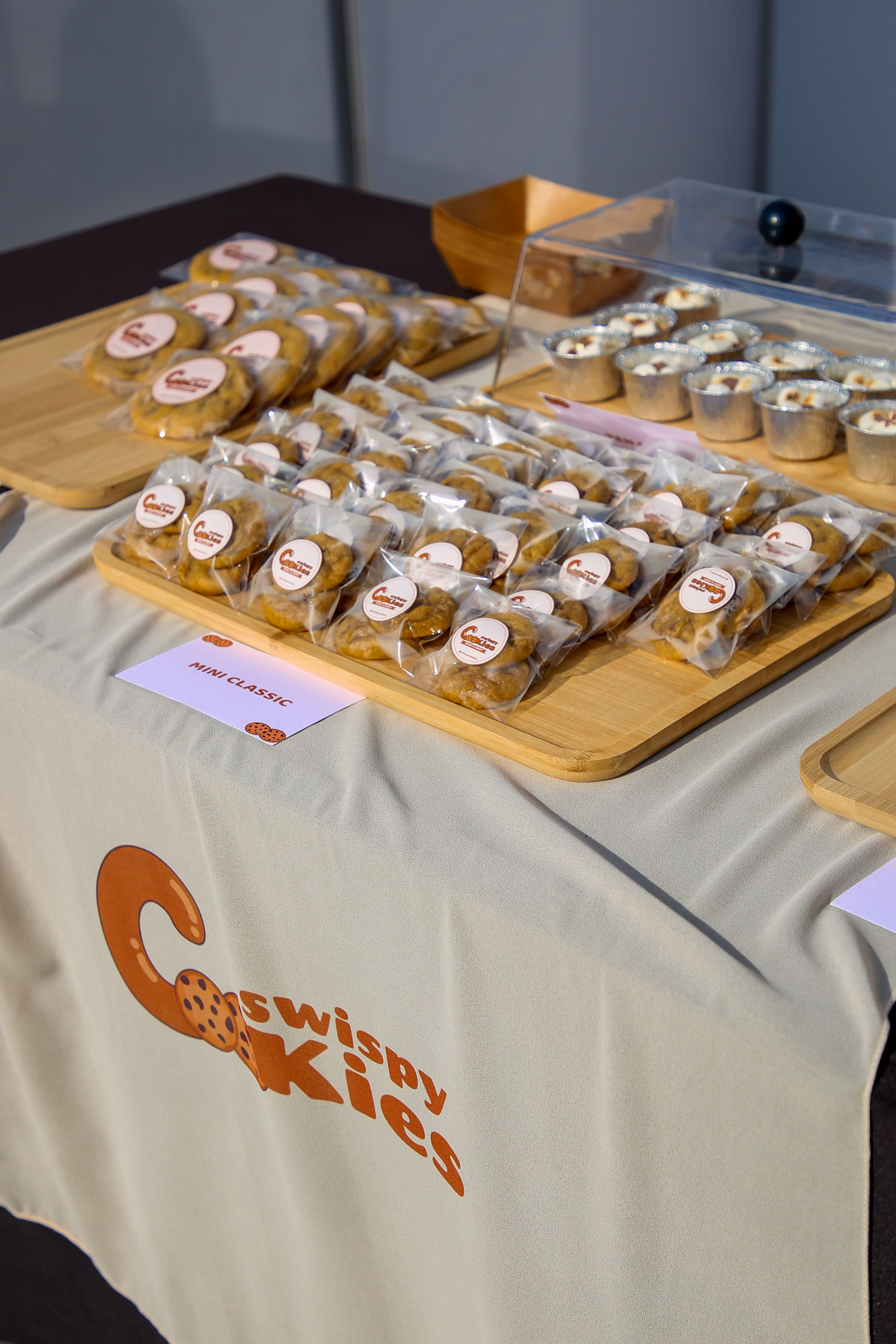 Trays of bagged cookies laid out across a vendor's table beneath a hand-labelled 'Mini Classic' card.